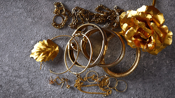 Image: An assortment of gold jewelry laid out against a grey background.