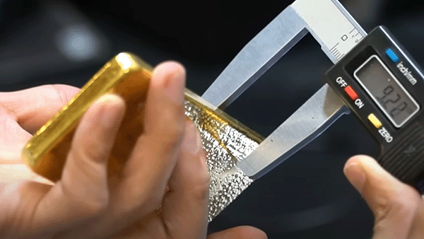 Measuring a gold bar with a digital caliper
